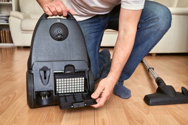 Repairman replacing an air filter in a vacuum cleaner at home on the floor